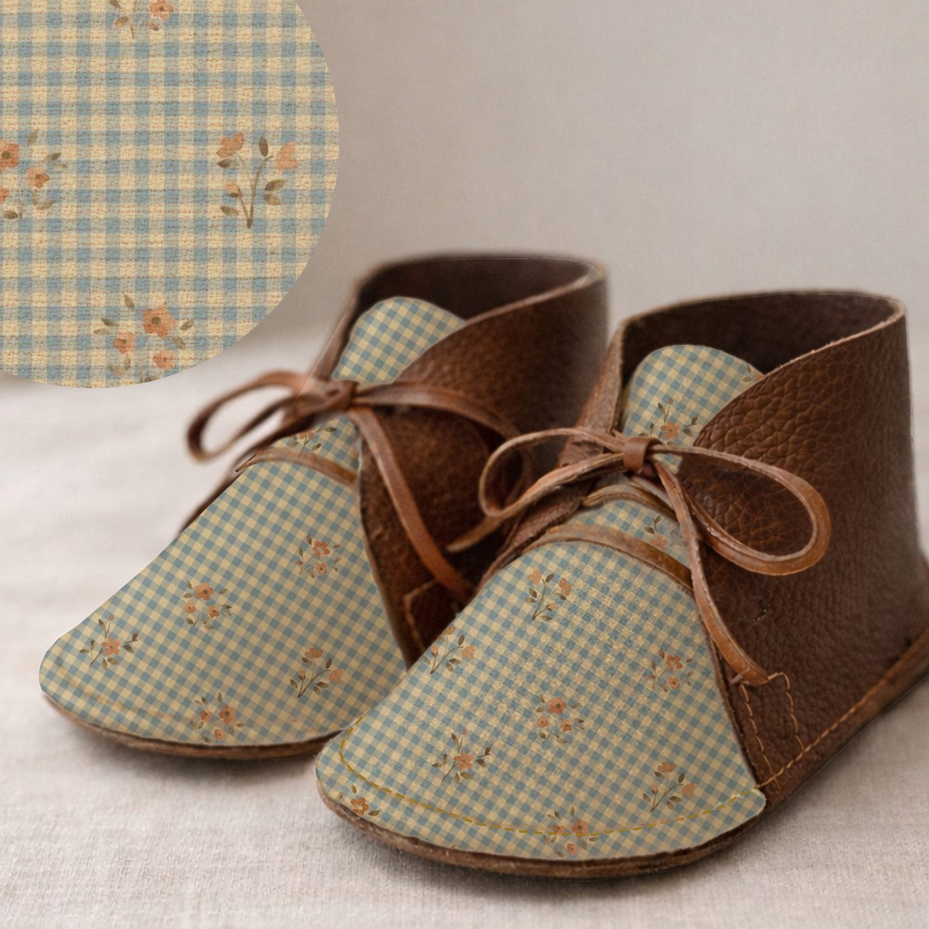 Pair of baby shoes with blue checkered pattern and brown leather accents on a light background