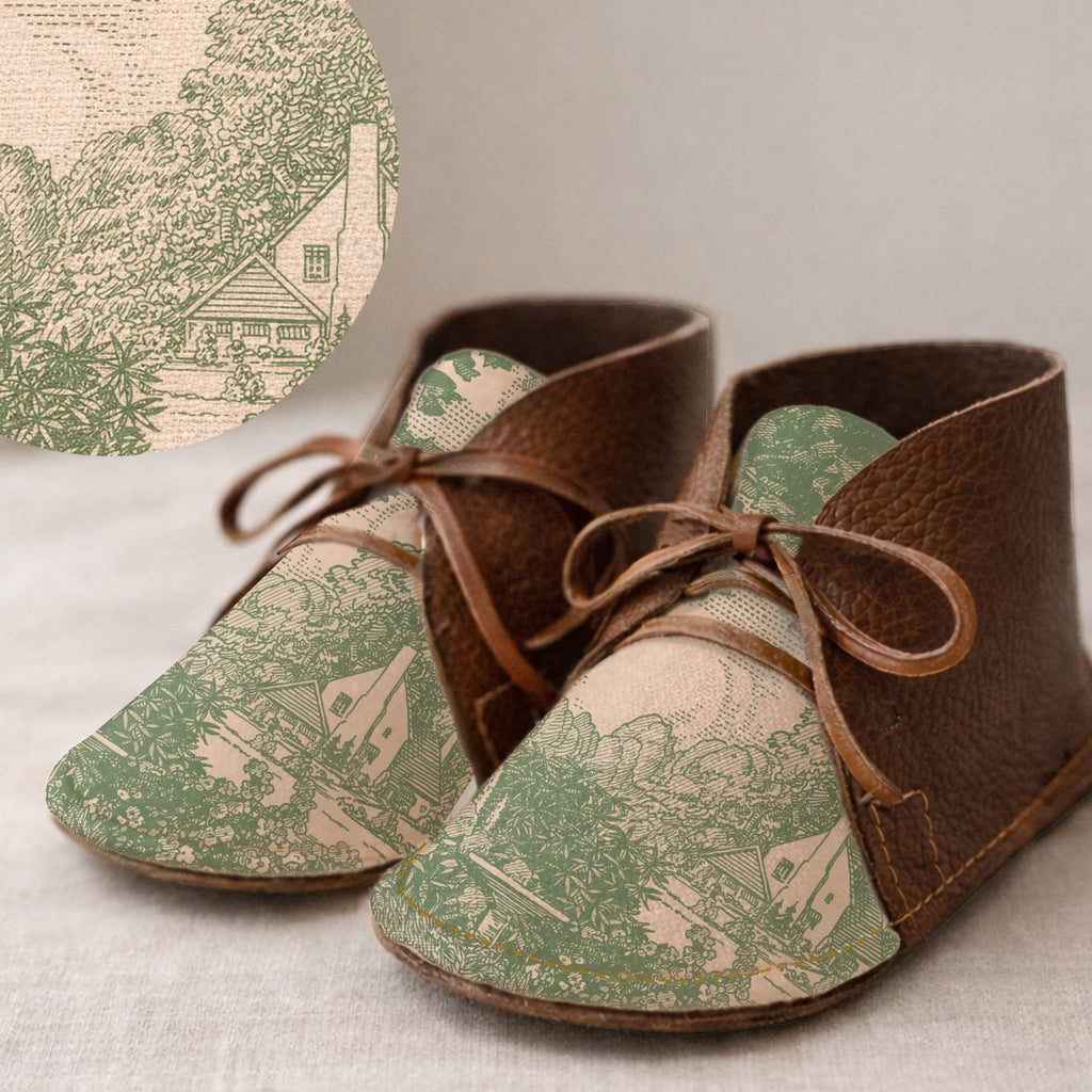 Pair of brown leather shoes with green pattern on a textured surface.