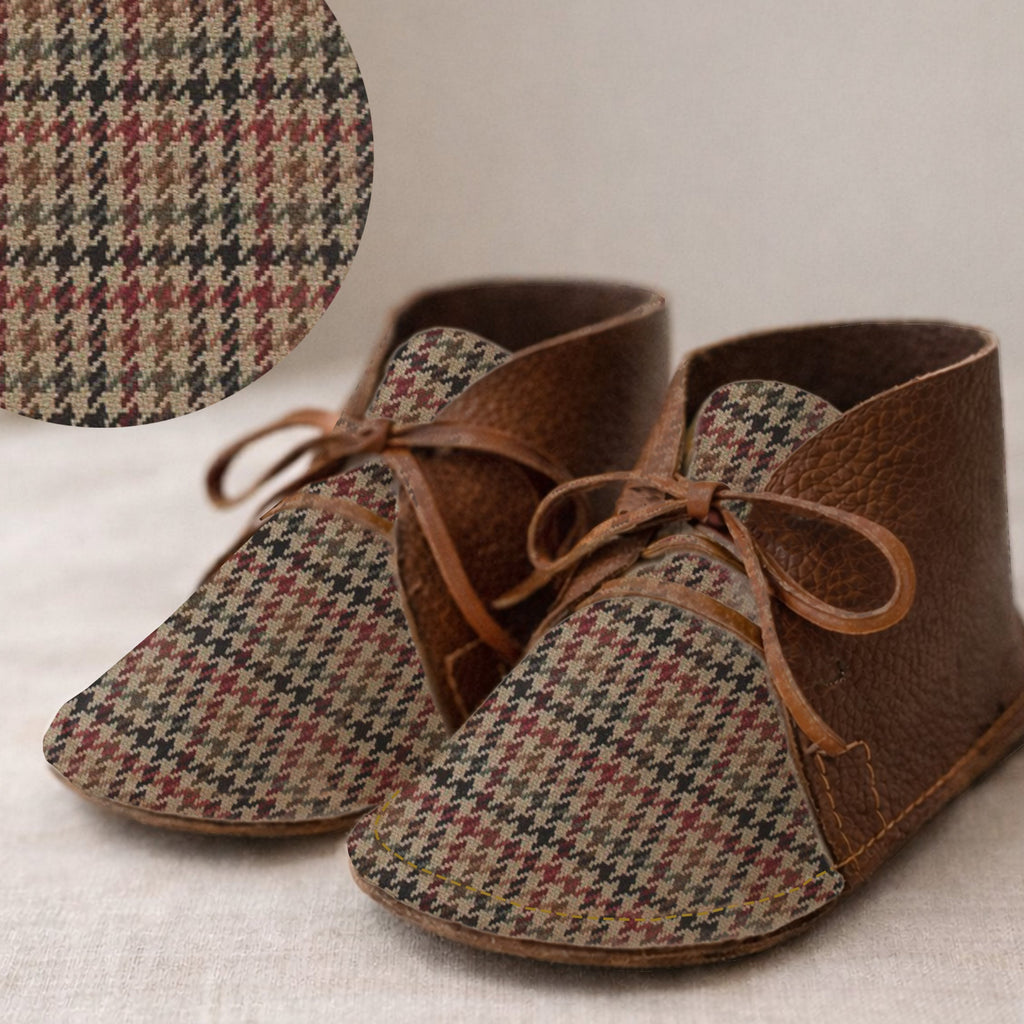 Pair of brown and houndstooth baby shoes on a neutral background