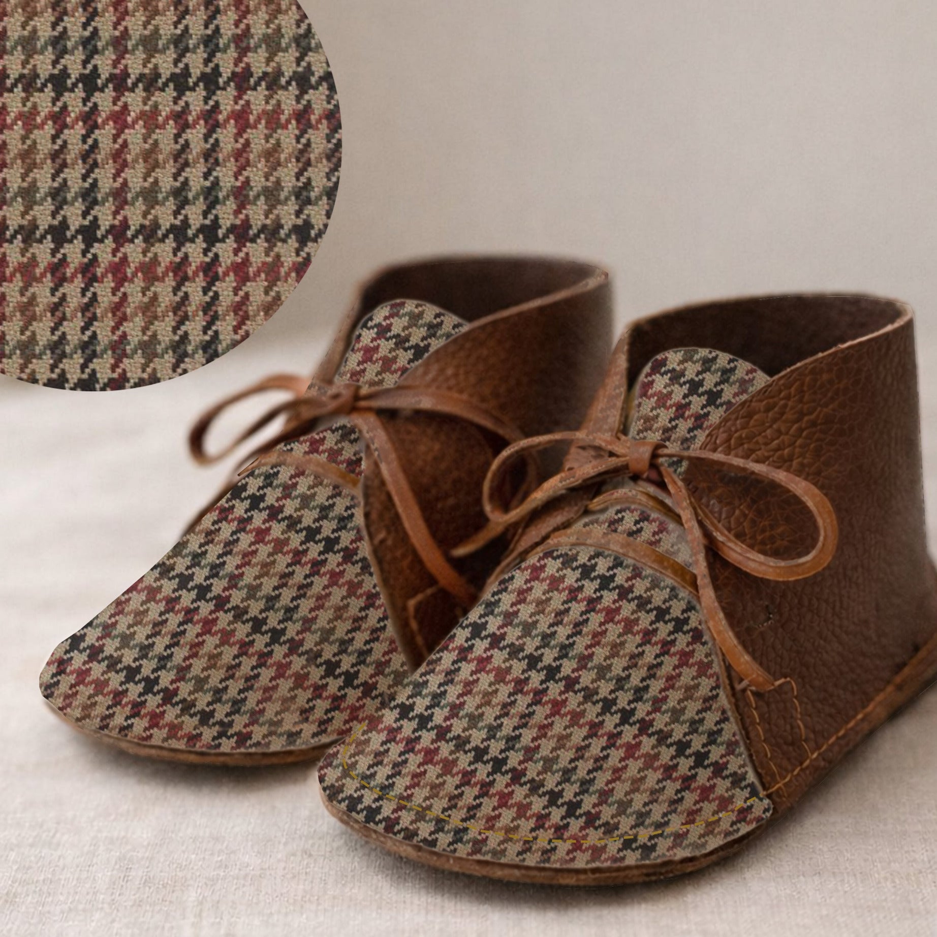 Pair of brown and houndstooth baby shoes on a neutral background