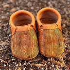 Pair of small brown leather shoes with wood grain pattern on a textured brown surface